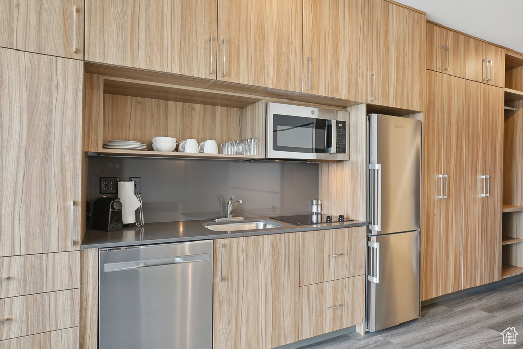 Kitchen with light brown cabinetry, stainless steel appliances, open shelves, and a sink