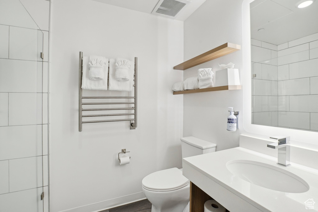 Bathroom featuring vanity, toilet, visible vents, radiator heating unit, and a shower