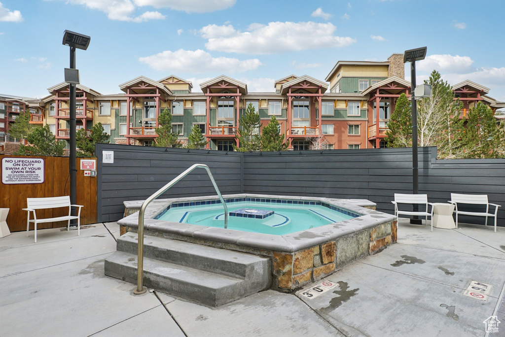 View of swimming pool featuring fence, a residential view, and a hot tub