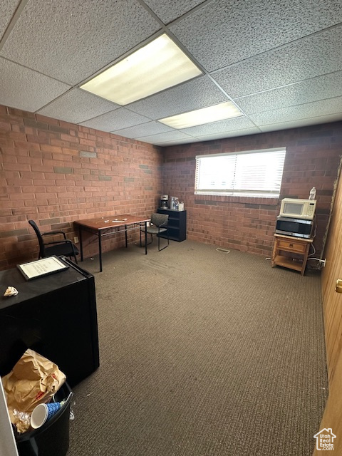 Interior space featuring a paneled ceiling and brick wall