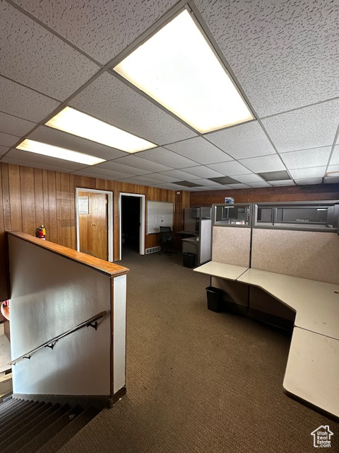 Interior space with carpet, a drop ceiling, and wooden walls