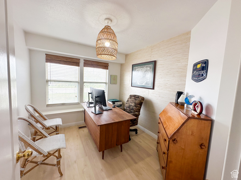Home office with an accent wall, light wood-style flooring, and baseboards