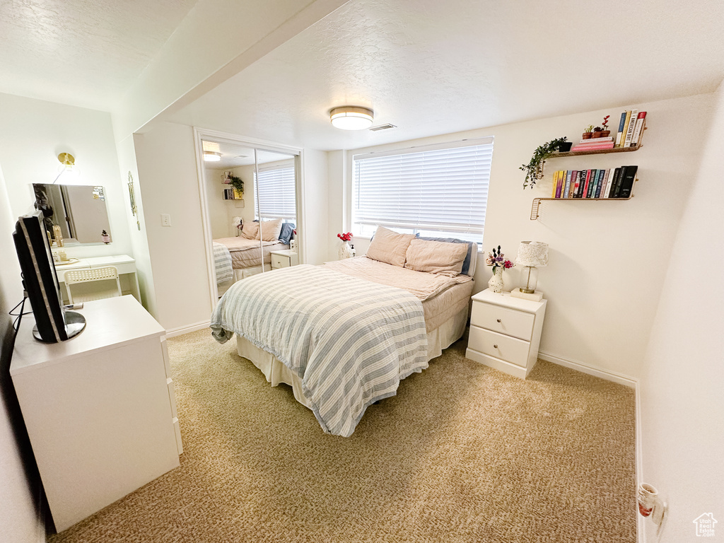 Bedroom featuring light carpet, baseboards, and a textured ceiling