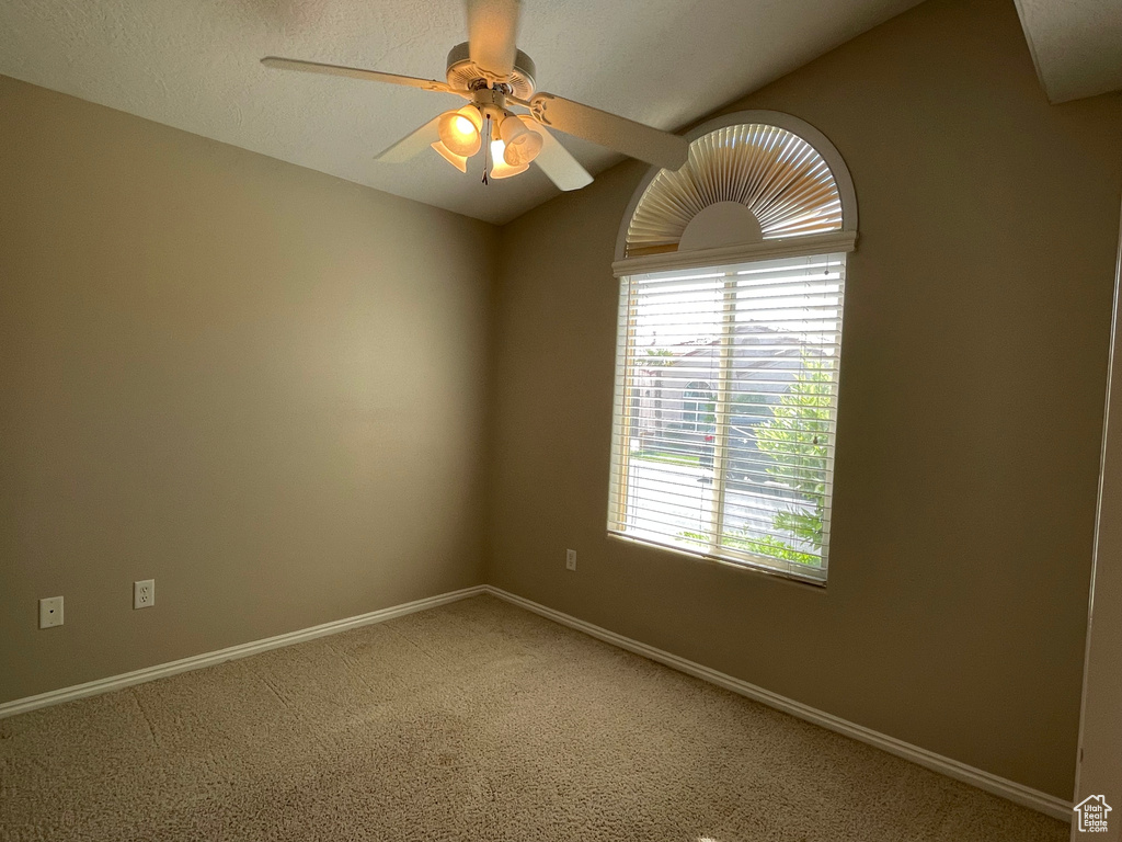 Spare room featuring ceiling fan, baseboards, light carpet, and a healthy amount of sunlight