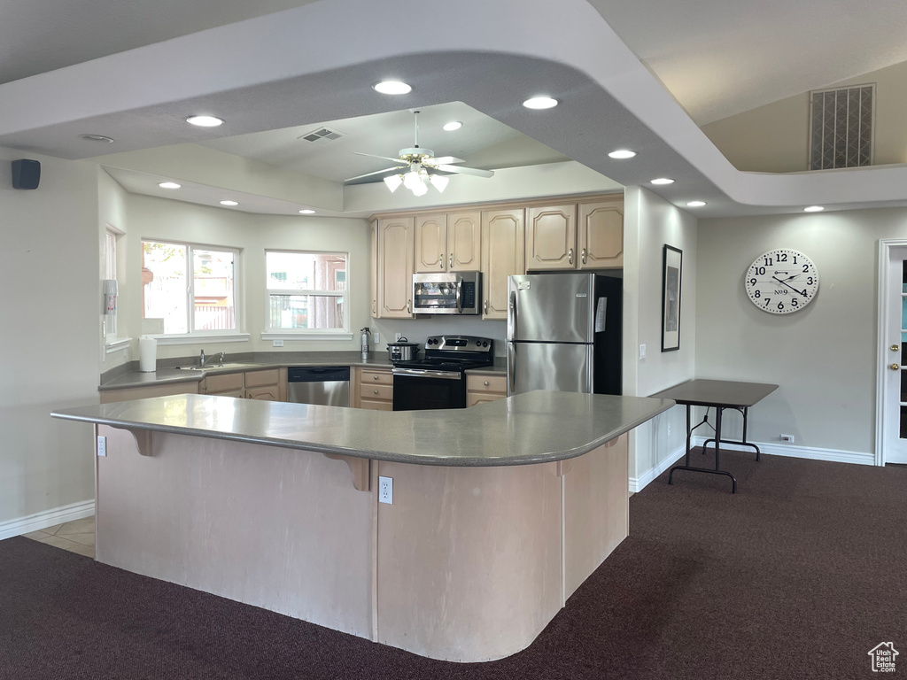 Kitchen with appliances with stainless steel finishes, a breakfast bar, visible vents, and light brown cabinetry