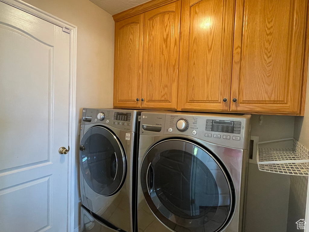 Washroom featuring washer and clothes dryer and cabinet space