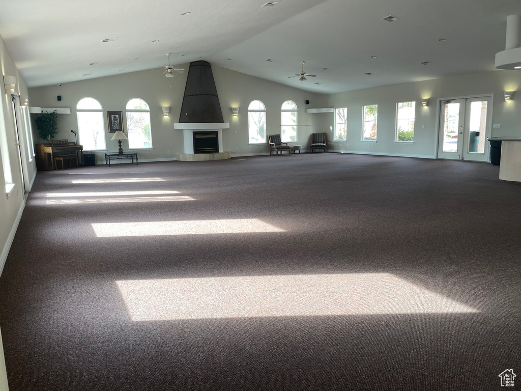 Unfurnished living room featuring lofted ceiling, carpet flooring, ceiling fan, plenty of natural light, and a fireplace