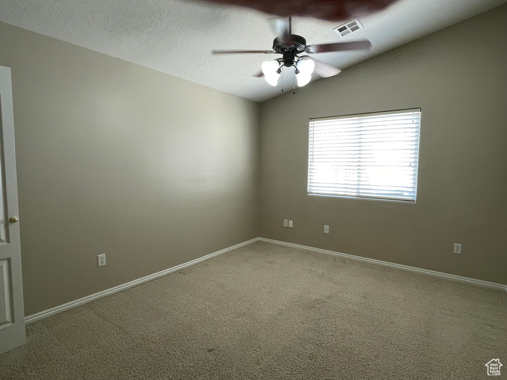 Carpeted empty room with a textured ceiling, visible vents, a ceiling fan, and baseboards