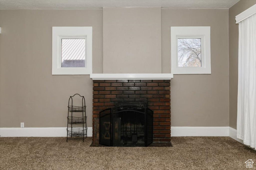 Room details featuring baseboards, carpet, and a brick fireplace