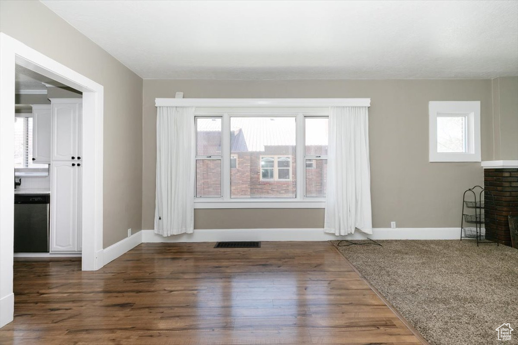 Unfurnished living room featuring baseboards, a brick fireplace, wood finished floors, and visible vents