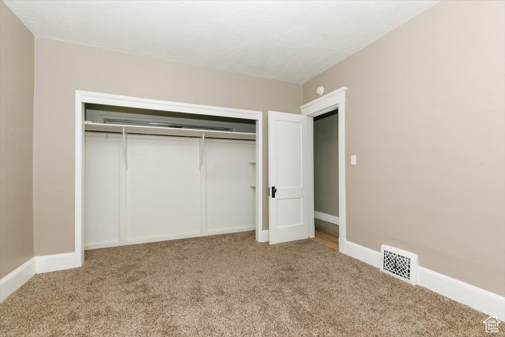 Unfurnished bedroom featuring visible vents, carpet, and a closet