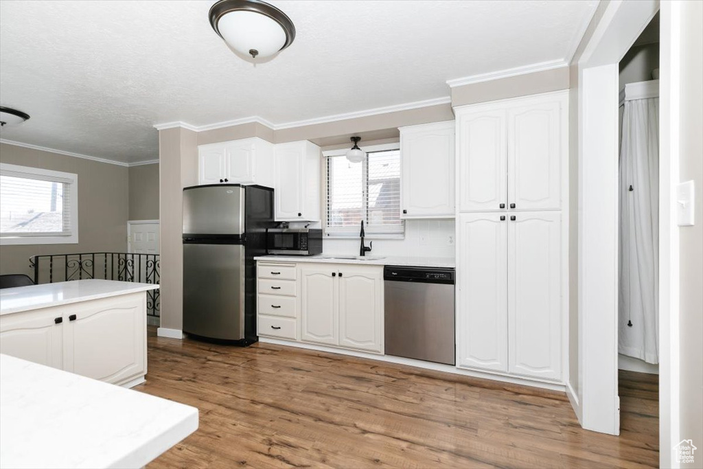 Kitchen with plenty of natural light, a sink, appliances with stainless steel finishes, and white cabinets