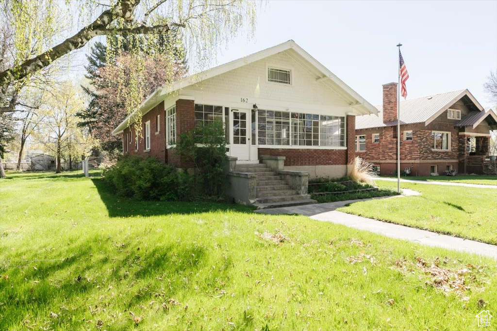 Bungalow-style house with brick siding and a front yard