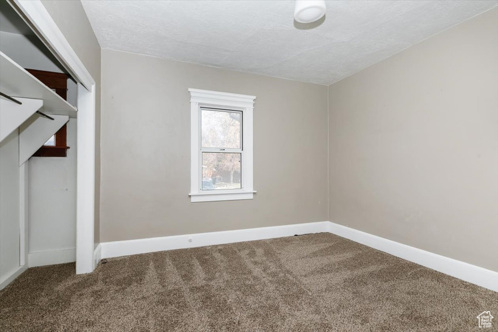 Unfurnished bedroom with baseboards, carpet, a closet, and a textured ceiling