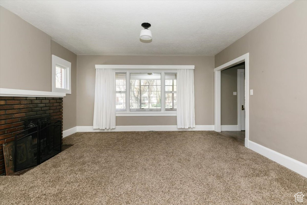 Unfurnished living room with carpet floors, baseboards, and a fireplace
