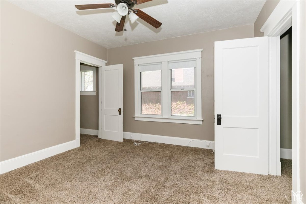 Unfurnished bedroom featuring baseboards, ceiling fan, carpet, and a textured ceiling
