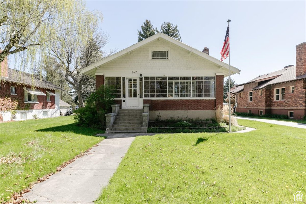 Bungalow-style home featuring brick siding and a front yard