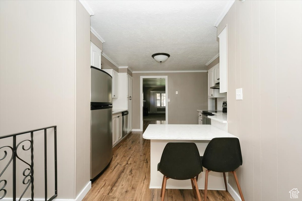 Kitchen featuring a peninsula, light wood-style floors, light countertops, white cabinetry, and stainless steel appliances