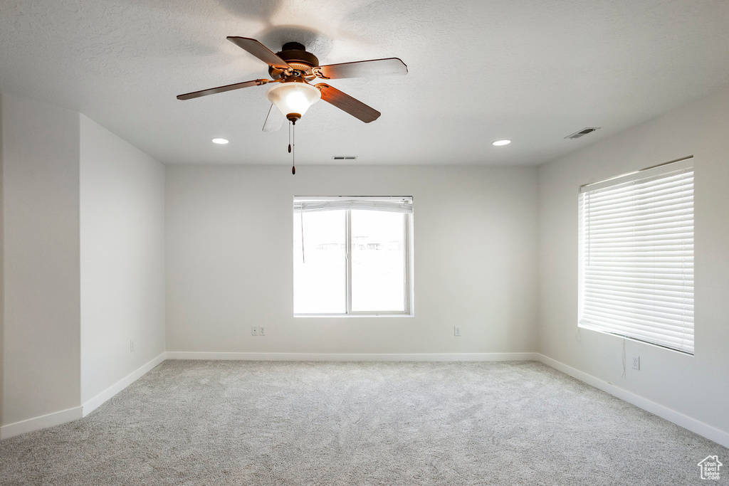 Unfurnished room featuring light colored carpet, visible vents, ceiling fan, and baseboards