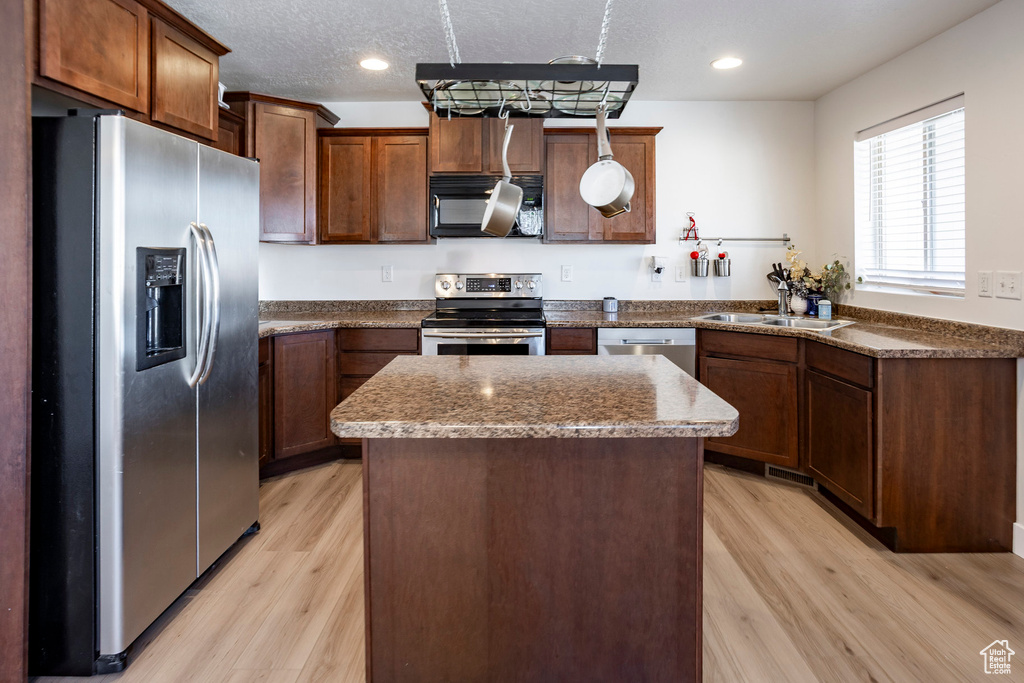 Kitchen featuring light wood finished floors, a sink, a kitchen island, and stainless steel appliances