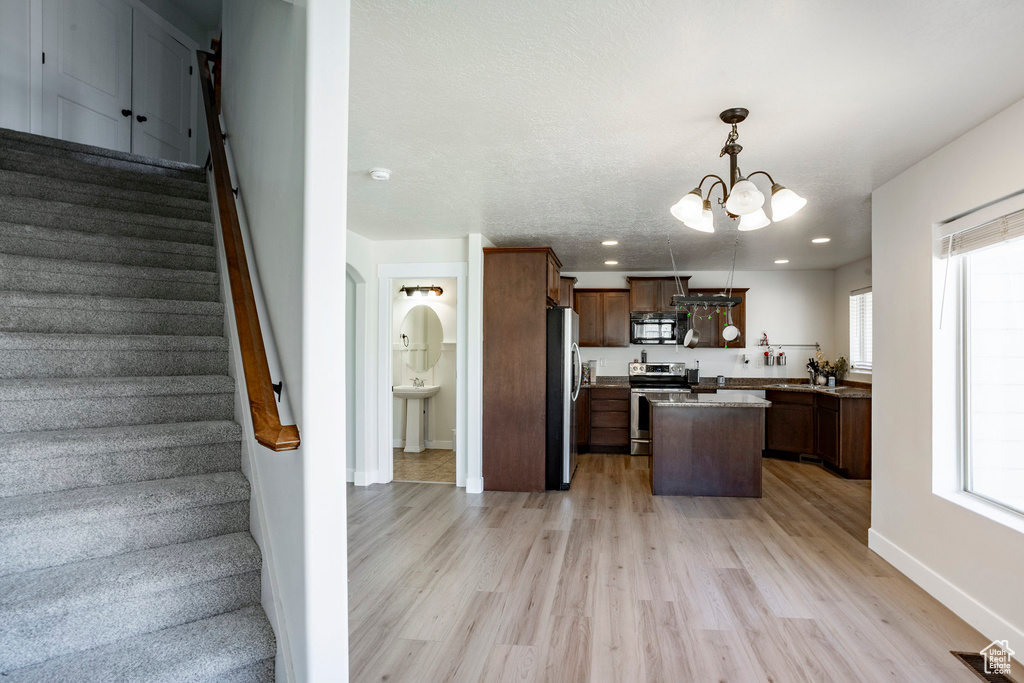 Kitchen with visible vents, light wood-type flooring, a notable chandelier, and appliances with stainless steel finishes