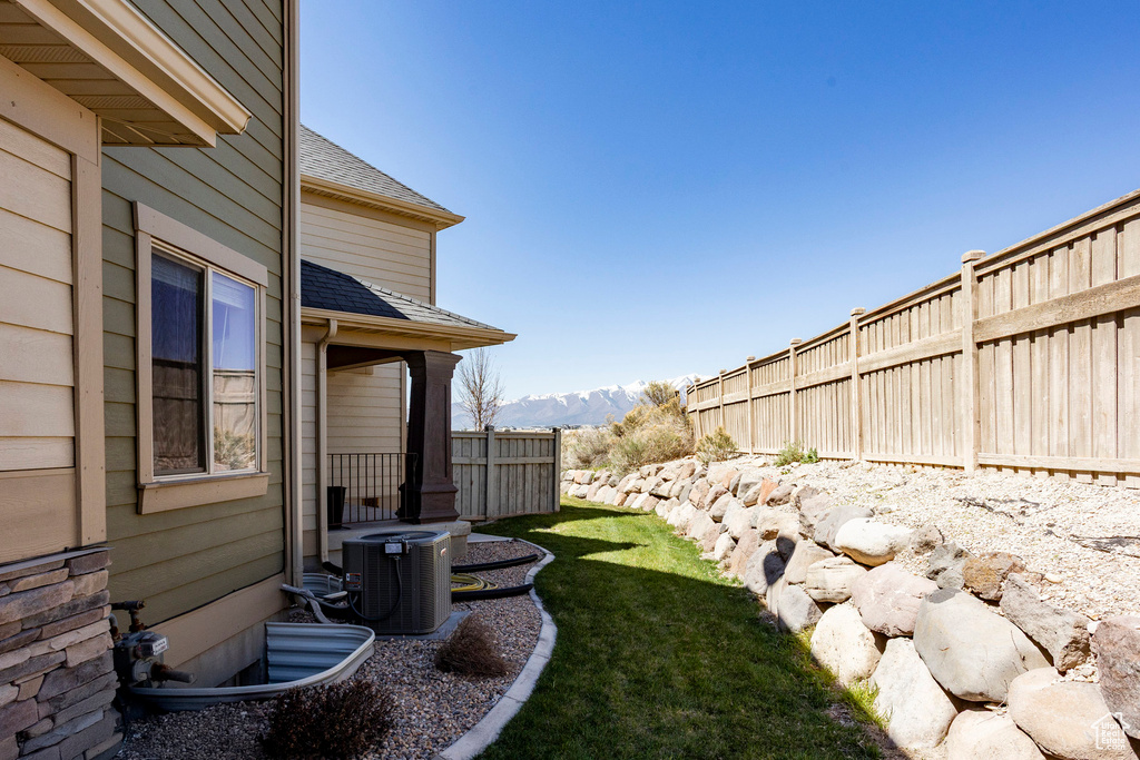 View of yard with fence, central AC unit, and a mountain view