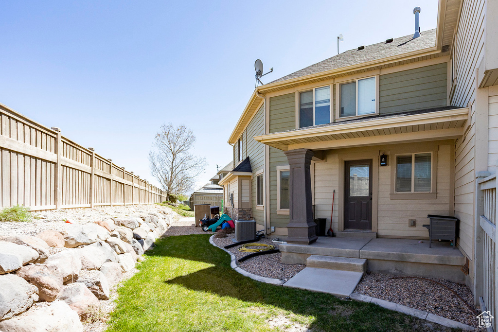 Rear view of property featuring a yard, central AC, and fence