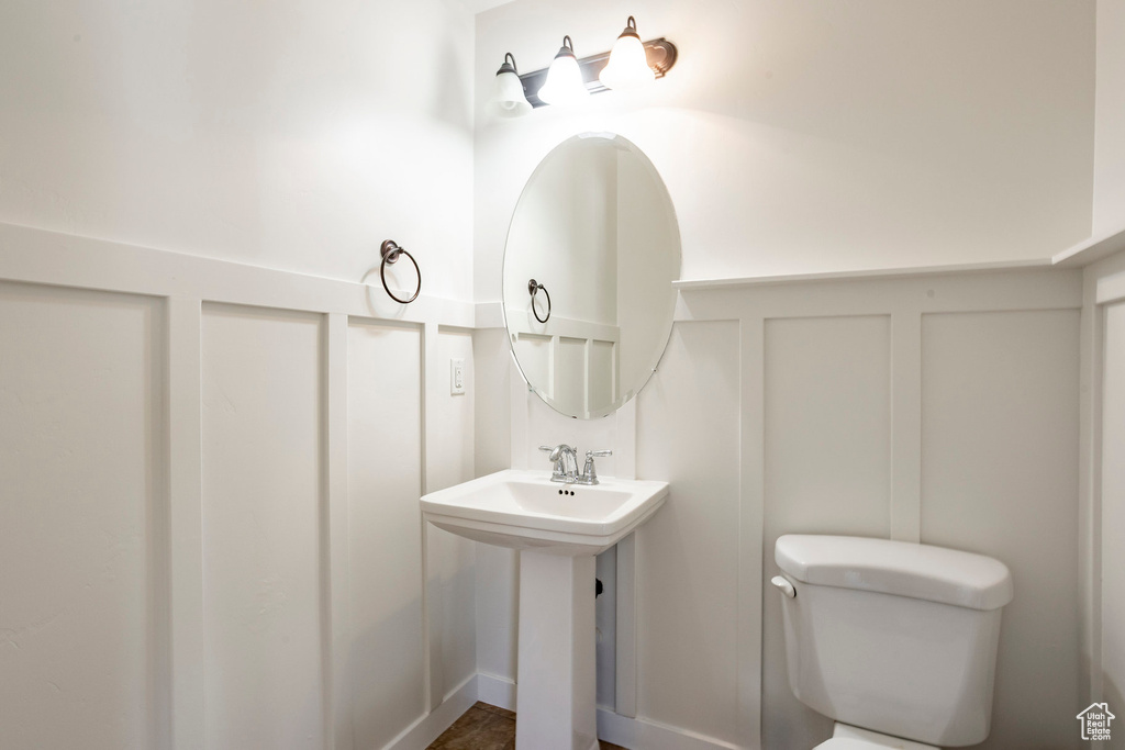 Bathroom with a decorative wall, toilet, and a wainscoted wall