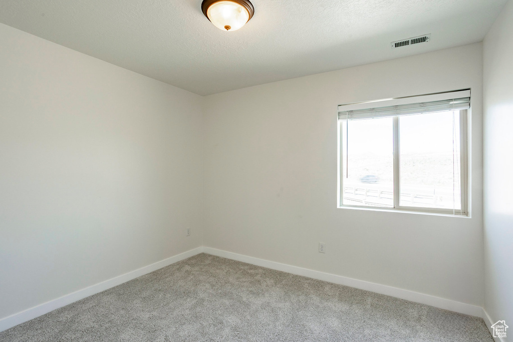 Spare room with visible vents, baseboards, and light carpet
