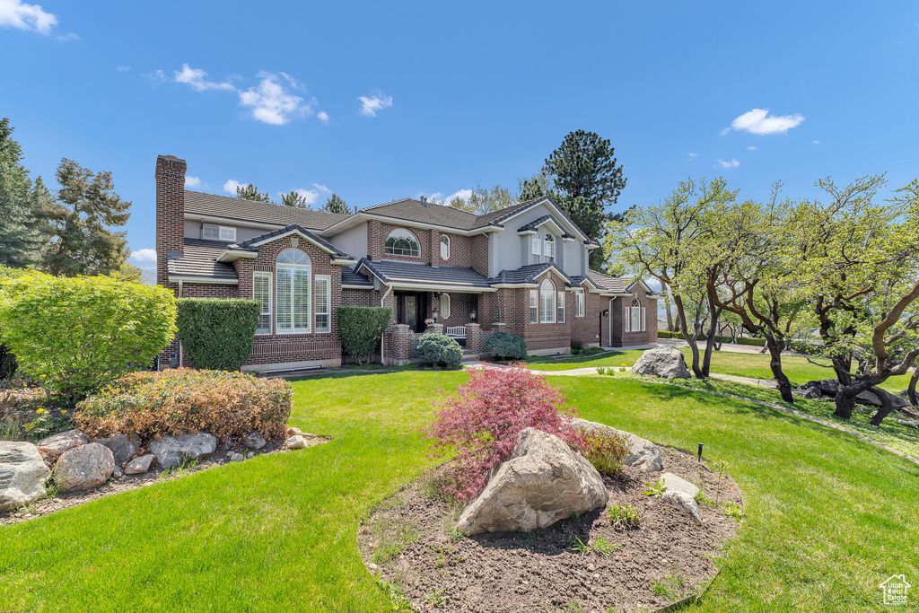 View of front of property with a front lawn, brick siding, and a chimney