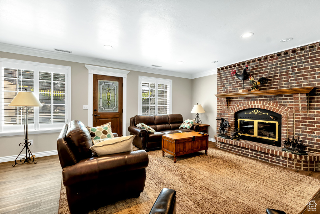 Living area with recessed lighting, wood finished floors, crown molding, baseboards, and a fireplace