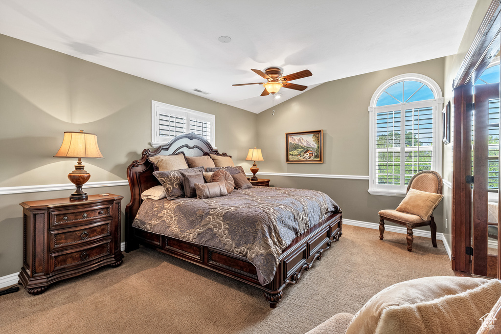 Carpeted bedroom with ceiling fan, visible vents, baseboards, and multiple windows