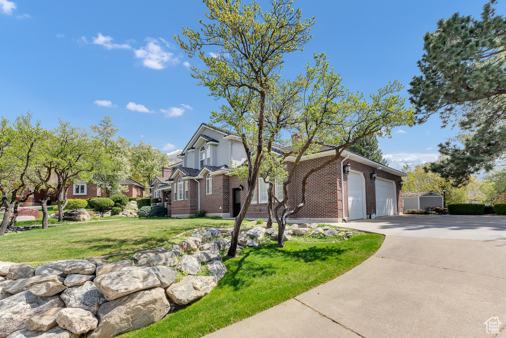 View of front of property with a front lawn, driveway, brick siding, and a residential view