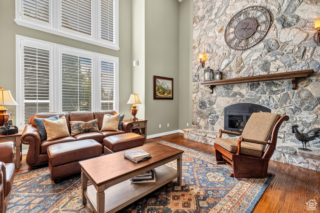 Living area with baseboards, a towering ceiling, wood finished floors, and a fireplace