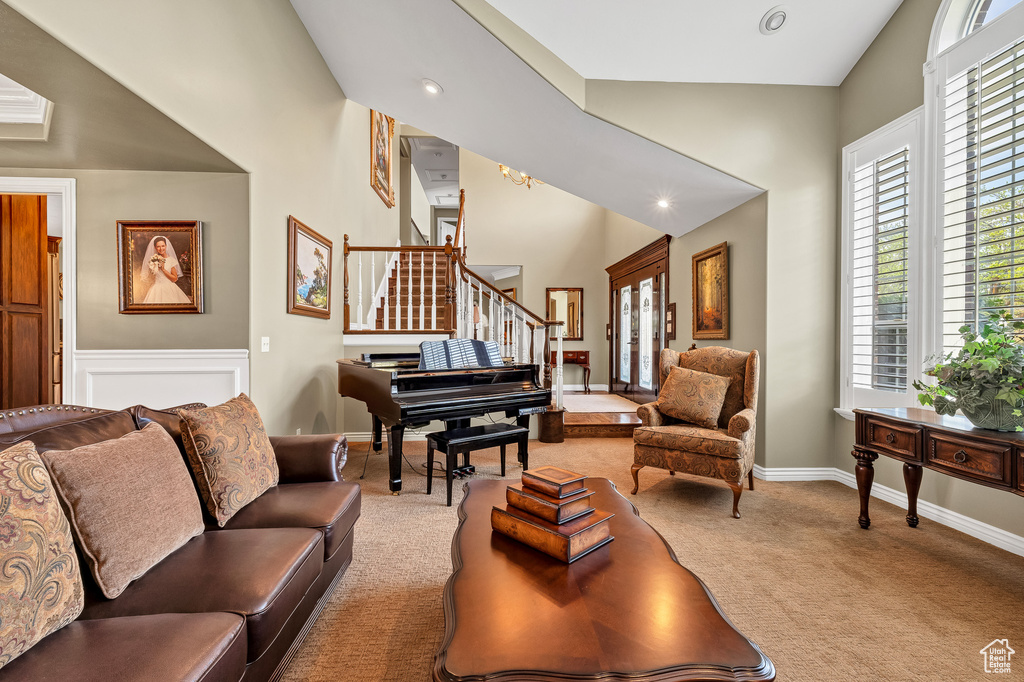 Living room featuring carpet flooring, baseboards, recessed lighting, stairs, and high vaulted ceiling