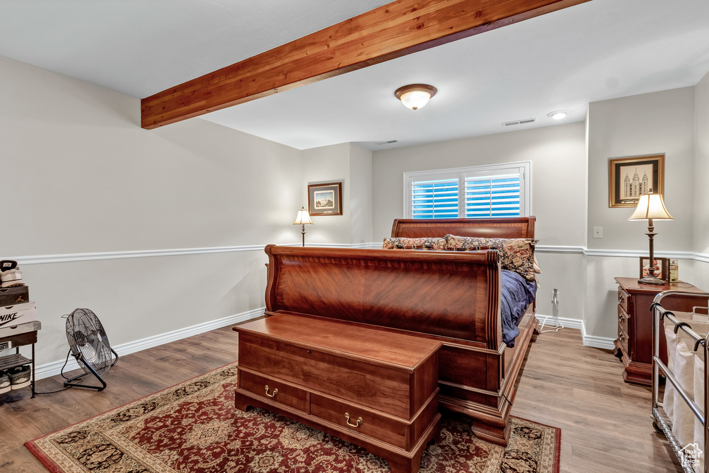 Bedroom featuring baseboards, beamed ceiling, wood finished floors, and visible vents