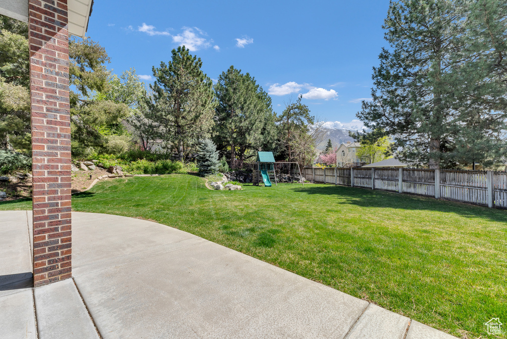 View of yard with fence, a mountain view, and a playground