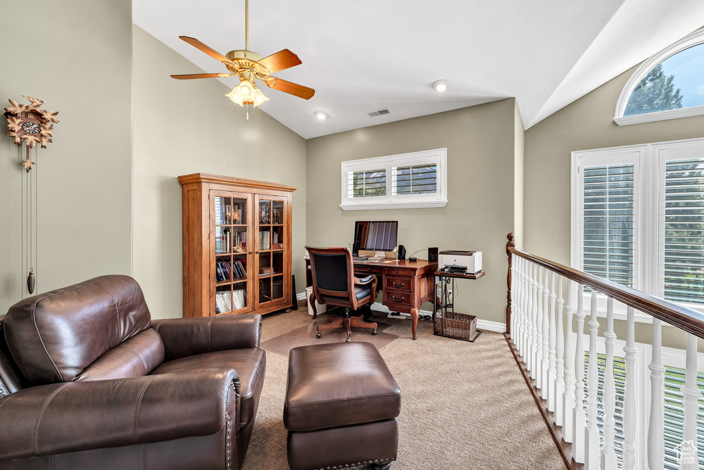 Office area featuring visible vents, a ceiling fan, light colored carpet, baseboards, and high vaulted ceiling