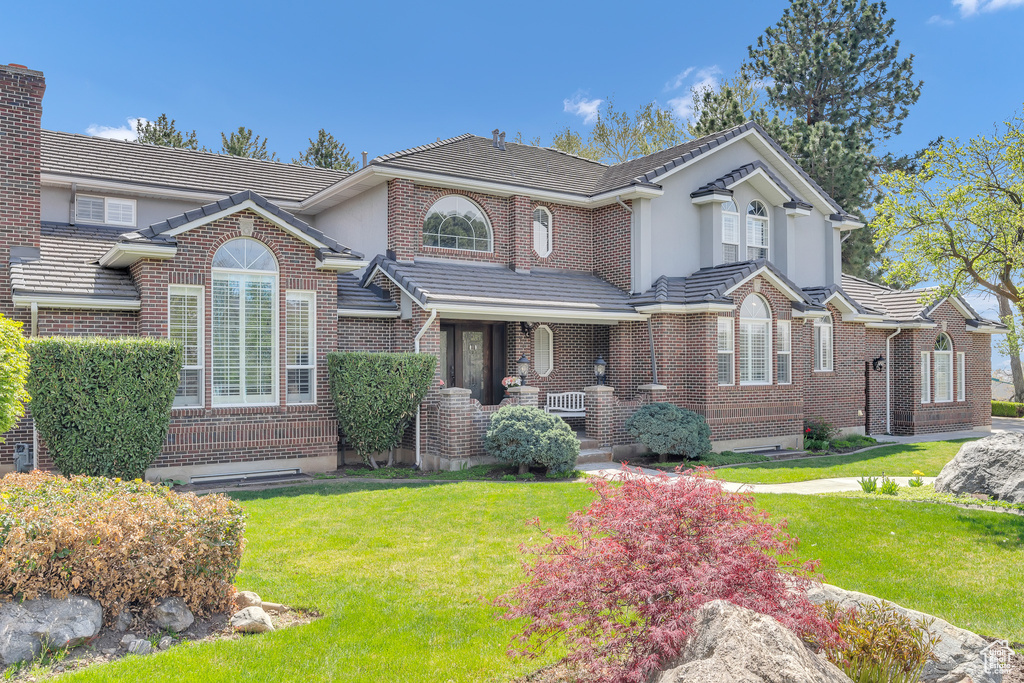 View of front of property with a tile roof, a front yard, and covered porch