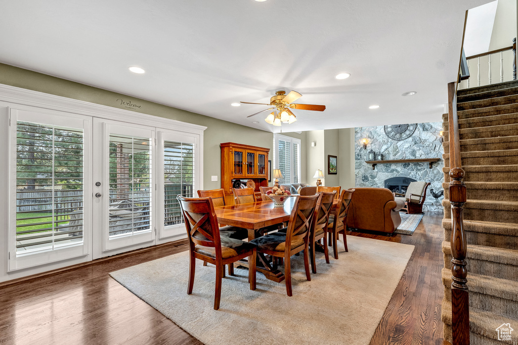 Dining space featuring recessed lighting, wood finished floors, ceiling fan, stairway, and a fireplace
