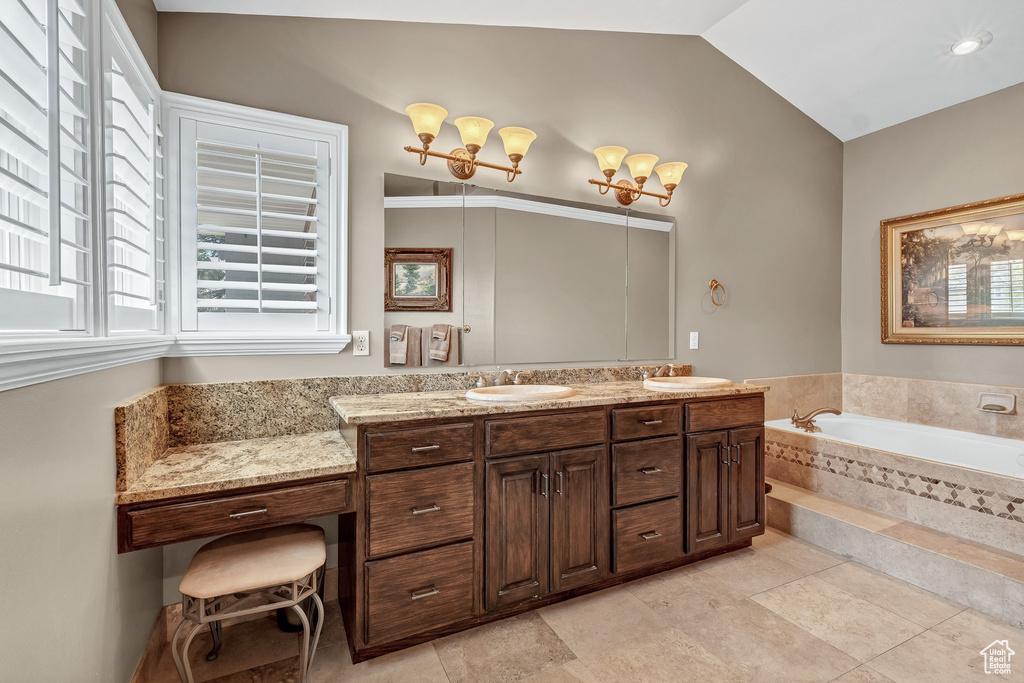 Full bath with a garden tub, vaulted ceiling, a sink, and double vanity