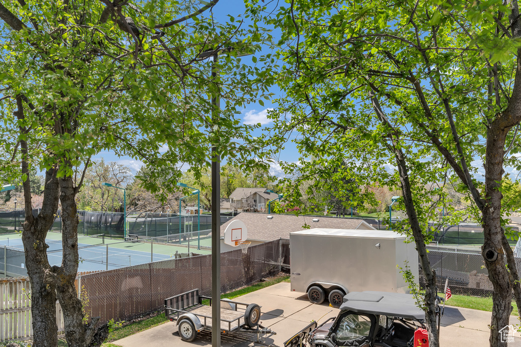 View of patio featuring fence and a tennis court