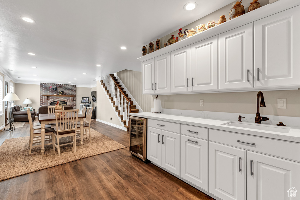 Kitchen with wine cooler, a sink, open floor plan, baseboards, and white cabinetry