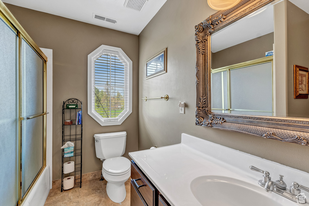 Full bathroom with shower / bath combination with glass door, visible vents, toilet, and vanity