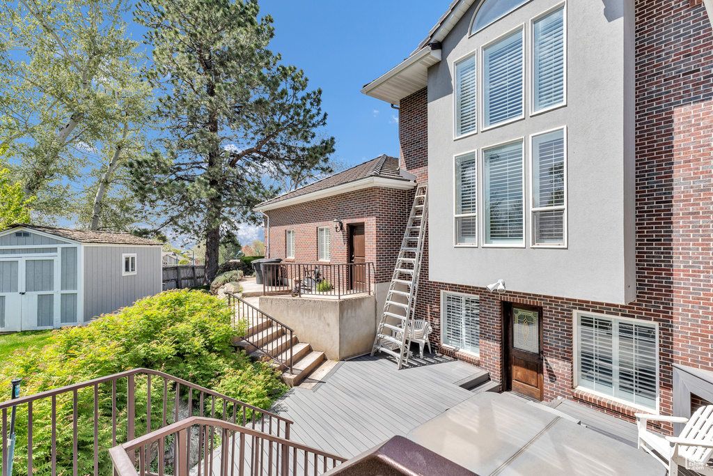 Deck featuring an outbuilding, a storage shed, and stairs