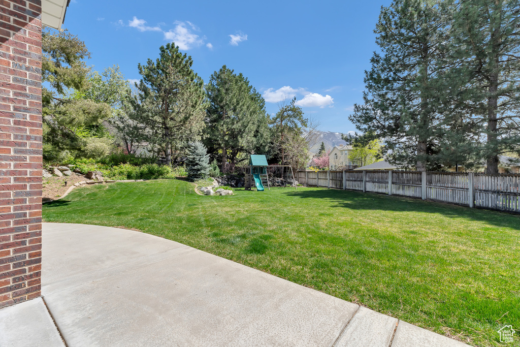 View of yard with a patio area, a playground, and fence