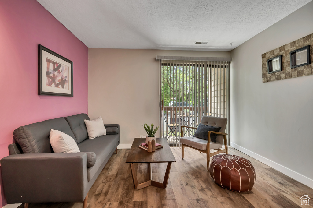Living room featuring baseboards, wood finished floors, and a textured ceiling