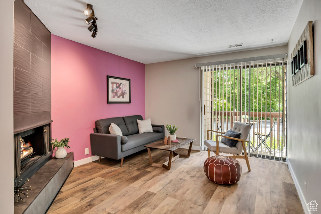 Living area featuring wood finished floors, a textured ceiling, baseboards, and a fireplace