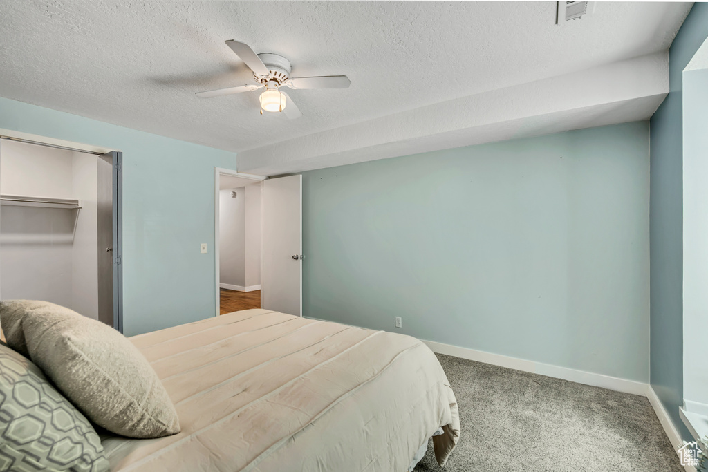 Bedroom with a textured ceiling, baseboards, a ceiling fan, and carpet floors