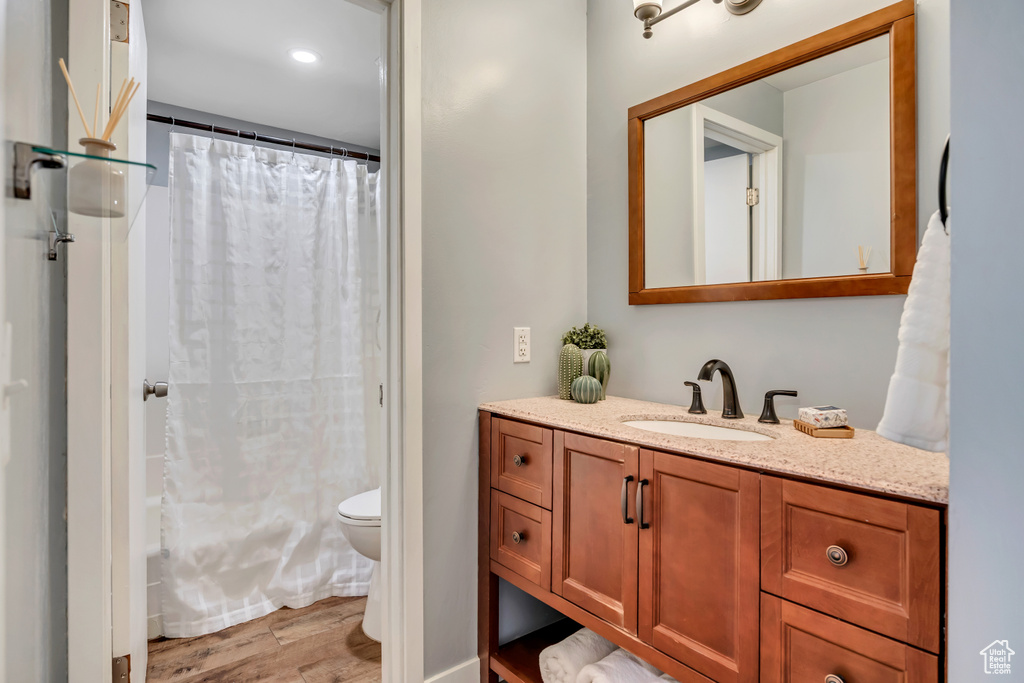 Full bathroom with wood finished floors, vanity, toilet, and shower / tub combo with curtain